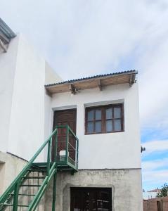 a white building with a green staircase in front of it at La Mejor-A in Comandante Luis Piedra Buena