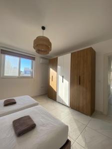 a white bedroom with two beds and a large window at Marija Block St Julian's Apartments in Is-Swieqi
