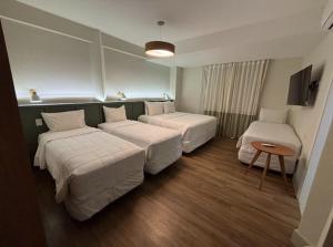 a hotel room with two beds and a table at Hotel Fazenda Brisa Itu in Itu