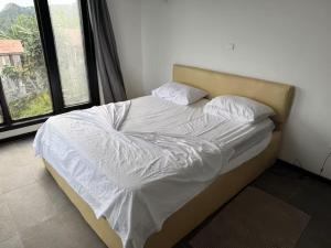 a bed with white sheets and pillows in a bedroom at Villa Sete Ondas in Ribeira Afonso