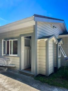 a small house with a door and a porch at Ruby Bay Beach Sleepout - 30 mins from Abel Tasman in Mapua