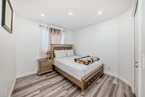 a white bedroom with a bed and a nightstand at Cozy Vacation Home in Calgary