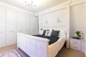 a white bedroom with a white bed and a chandelier at 90A Tower Road in Newquay