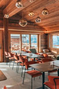 a dining room with tables and chairs and windows at Nînda Boutique Hôtel in Nendaz