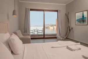 a bedroom with a bed and a view of the ocean at Bay View Suites & Apartments in Marathias