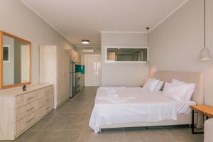 a large bedroom with a white bed and a kitchen at Bay View Suites & Apartments in Marathias