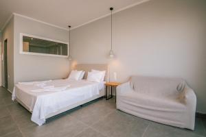 a bedroom with a white bed and a chair at Bay View Suites & Apartments in Marathias