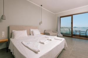 a bedroom with a large white bed and a balcony at Bay View Suites & Apartments in Marathias +33 photos