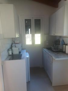 a white kitchen with white cabinets and a sink at Villa Macky Cottage in Kato Almiri