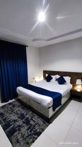 a bedroom with a large bed with a blue curtain at المبيت 2 جديد in Abha