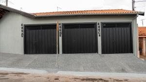 a garage with two black doors on a house at Jahu Center Casas Un 4 in Jaú