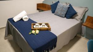 a bedroom with a bed with blue sheets and a tray at Jahu Center Casas Un 4 in Jaú