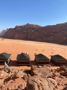a group of tents in the desert near a rock at Rum Panoramic Camp & Tour in Wadi Rum