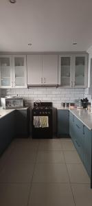 a kitchen with white cabinets and a black stove at Accomodation in Cape Town in Goodwood
