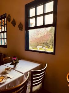 a table with a white table cloth and a window at Quinta dos Faisões in Santo Antônio do Pinhal