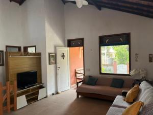 a living room with a couch and a television at Casa in Baia Formosa-Bùzios in Búzios