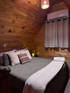 a bedroom with a bed in a wooden cabin at Cabanas Paxixi - Mirante in Camisão +50 photos