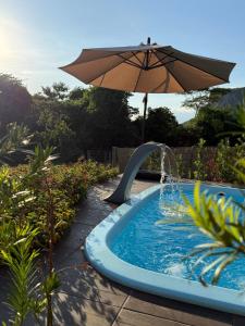 a swimming pool with an umbrella and a water slide at Cabanas Paxixi - Mirante in Camisão