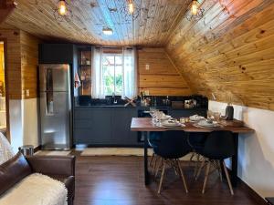 a kitchen with a wooden ceiling and a table with chairs at Cabanas Paxixi - Mirante in Camisão