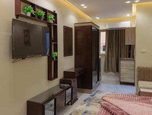 a living room with a flat screen tv on a wall at Hana Grand Hotel in Madinat Al Ashir min Ramadan