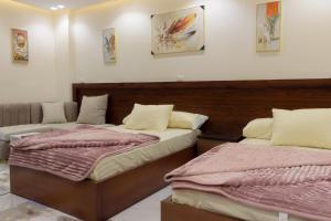 two beds in a room with two bedsvisor at Hana Grand Hotel in Madinat Al Ashir min Ramadan