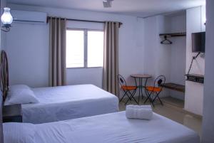 a hotel room with two beds and a table and chairs at Hotel Posada del Angel in Mérida