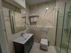 a white bathroom with a sink and a shower at Vila Bomond in Edineţ