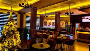 a christmas tree in a restaurant with tables and chairs at Hotel Diamant in Tropojë