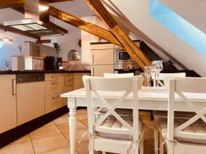 a kitchen with a white table and white chairs at Groasmückle Apartment in Tauberbischofsheim