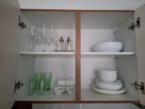 a cabinet filled with glasses and plates and bowls at Cosy central apartment in Litija