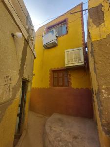 an alley with a yellow building with a air conditioner at moon guest house in Aswan