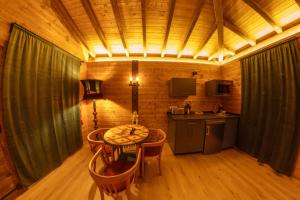 a kitchen with a table and chairs in a room at Pensión Cabañas Bosque Máxico de Bonxe in Outeiro de Rei