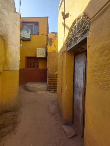 an alley with a yellow building with a door at moon guest house in Aswan +32 photos