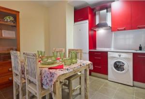 a kitchen with a table with chairs and red cabinets at Apartamentos turísticos Sardon in Sardón de los Frailes