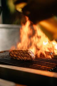 a piece of meat cooking on a grill with fire at Curaçao Marriott Beach Resort in Willemstad +160 photos