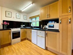 a kitchen with white appliances and wooden cabinets at Dabinett in Ledbury