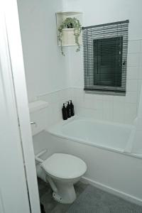 a white bathroom with a toilet and a bath tub at Contractor & Family Haven, Sleeps 7, Parking & Garden in Wednesfield +17 photos