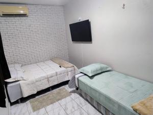 a room with two beds and a tv on the wall at Edícula Planalto in Manaus