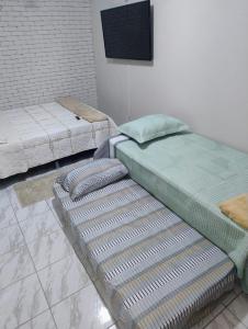 a room with two beds and a flat screen tv at Edícula Planalto in Manaus
