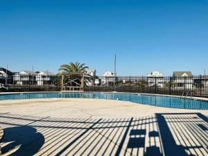 a large swimming pool with a playground in front of a fence at Dockside Dream Home for 10 in Galveston