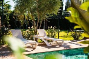 two white chairs sitting next to a swimming pool at Villa Dar Saada in Marrakesh