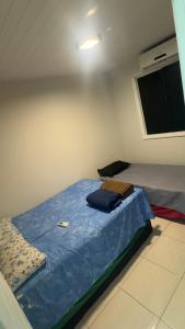a bedroom with a bed with blue sheets and a window at Casa aconchegante com piscina e wi-fi rápido in Aracaju