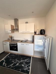 a kitchen with white cabinets and an open refrigerator at Kleines Appartment mit großer Terrasse in Herscheid