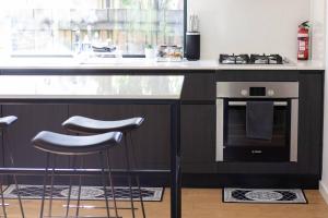 a kitchen with a stove and two bar stools at Lakes Edge 1 - 2BR Close to Lake in Wendouree +8 photos
