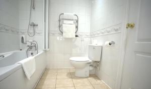 a white bathroom with a toilet and a bath tub at Consort Hotel & Urban Spa in Rotherham