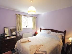 a bedroom with a bed with a dresser and a mirror at Wisteria Cottage in Aylsham