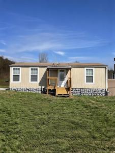 a mobile home with a porch on a grass field at The Cozy Cow Cottage in Bluefield