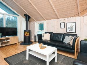 a living room with a black leather couch and a fireplace at 6 person holiday home in Toftlund-By Traum in Toftlund