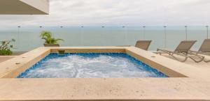 a swimming pool with chairs and the ocean in the background at Luxury Oceanfront Apartment Spiaggia 2BR 3BA Playa azul Cartagena in Cartagena de Indias +11 photos