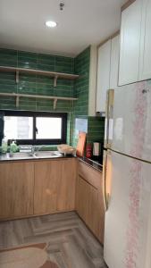 a kitchen with a white refrigerator and wooden cabinets at Niu Homestay in An Khê